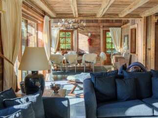 Experience rustic luxury in this charming wooden chalet, featuring a spacious living area with plush seating and a cozy dining space perfect for gatherings.