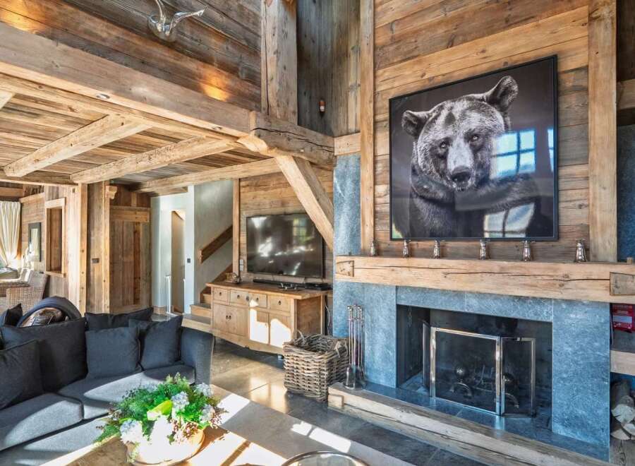Experience rustic luxury in this stunning mountain lodge living room, featuring a grand stone fireplace adorned with a captivating bear portrait.