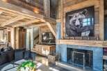 Experience rustic luxury in this stunning mountain lodge living room, featuring a grand stone fireplace adorned with a captivating bear portrait.