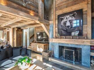 Experience rustic luxury in this stunning mountain lodge living room, featuring a grand stone fireplace adorned with a captivating bear portrait.