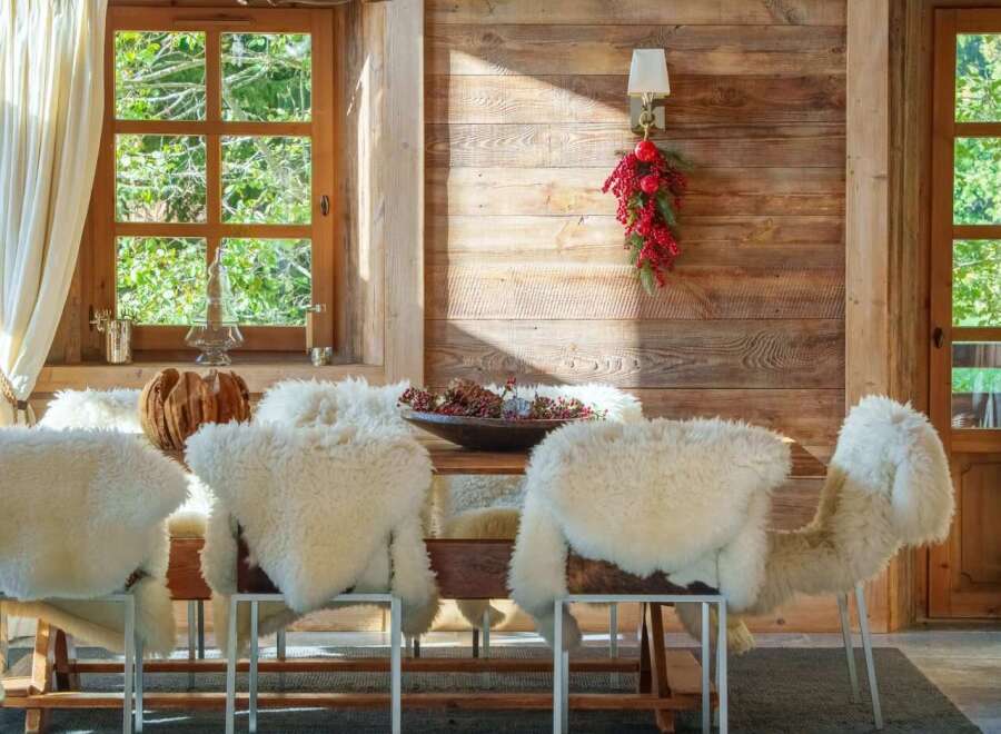 Experience rustic charm in this dining room, featuring a striking antler chandelier and cozy sheepskin-covered chairs.