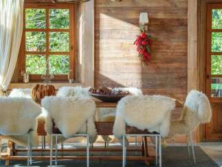 Experience rustic charm in this dining room, featuring a striking antler chandelier and cozy sheepskin-covered chairs.
