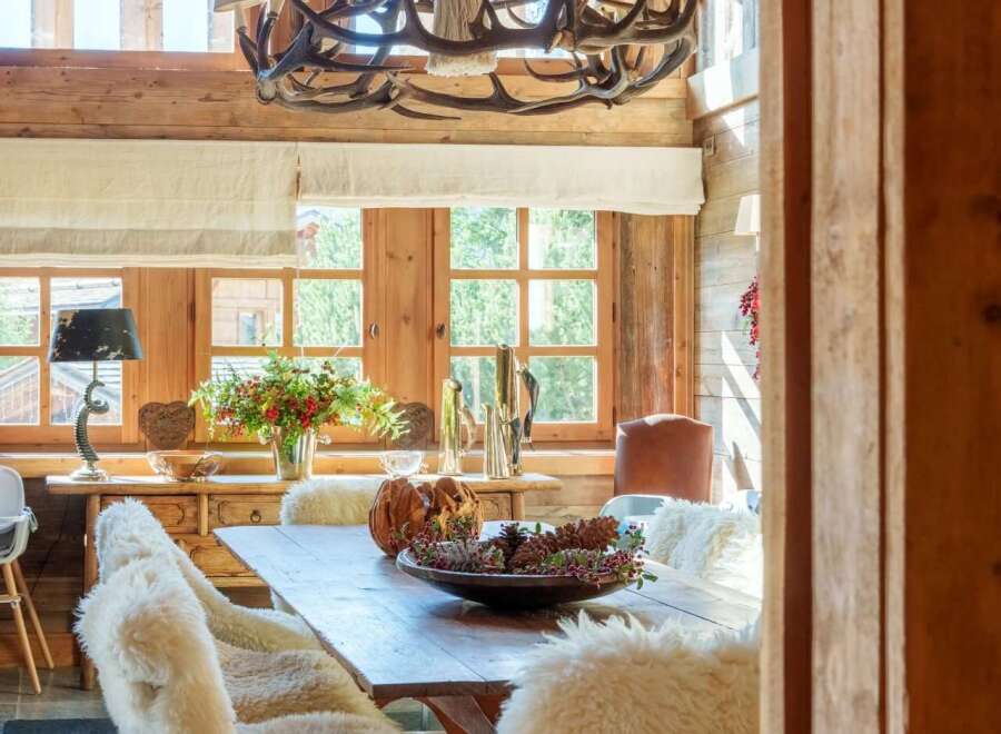 Experience rustic elegance in this charming dining room, featuring a magnificent antler chandelier that casts a warm glow.