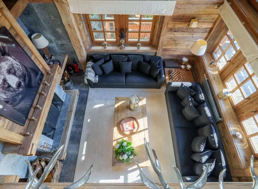 Experience rustic luxury in this stunning mountain chalet living room, featuring a grand stone fireplace adorned with a captivating bear portrait.