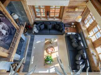 Experience rustic luxury in this stunning mountain chalet living room, featuring a grand stone fireplace adorned with a captivating bear portrait.