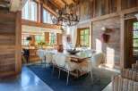 Experience rustic elegance in this charming dining room, featuring a grand antler chandelier and walls paneled with warm, reclaimed wood.