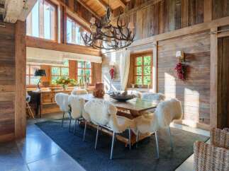Experience rustic elegance in this charming dining room, featuring a grand antler chandelier and walls paneled with warm, reclaimed wood.