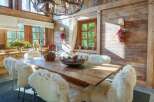 Experience rustic elegance in this charming dining room, featuring a large wooden table surrounded by plush, sheepskin-covered chairs.