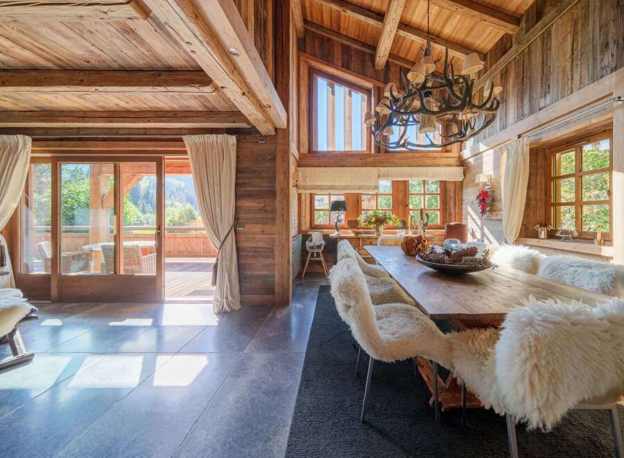 Experience rustic luxury in this stunning dining room, featuring a grand wooden table adorned with plush, sheepskin-covered chairs, perfect for intimate gatherings.