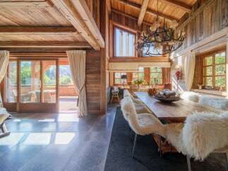 Experience rustic luxury in this stunning dining room, featuring a grand wooden table adorned with plush, sheepskin-covered chairs, perfect for intimate gatherings.