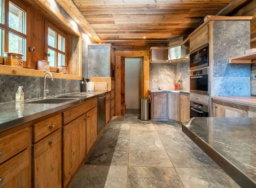 Experience rustic elegance in this charming kitchen, featuring warm wooden cabinetry and a natural stone backsplash.
