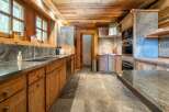 Experience rustic elegance in this charming kitchen, featuring warm wooden cabinetry and a natural stone backsplash.