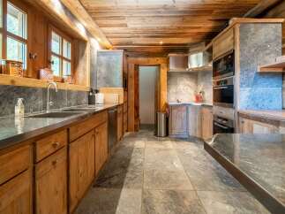 Experience rustic elegance in this charming kitchen, featuring warm wooden cabinetry and a natural stone backsplash.