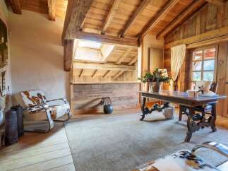 Experience rustic charm and modern comfort in this beautifully appointed room, featuring exposed wooden beams and a vaulted ceiling.