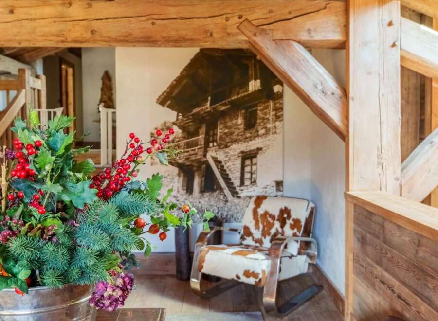 Experience rustic charm in this mountain retreat, featuring exposed wooden beams and a cozy armchair upholstered in cowhide.
