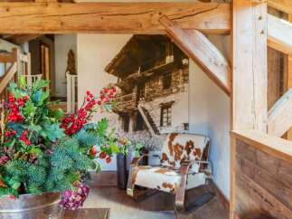 Experience rustic charm in this mountain retreat, featuring exposed wooden beams and a cozy armchair upholstered in cowhide.