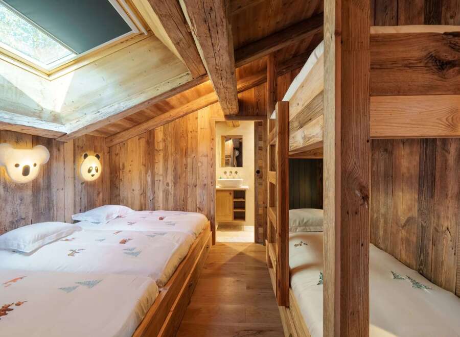 Experience cozy mountain living in this charming bedroom featuring rustic wooden walls and exposed beams.