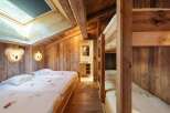 Experience cozy mountain living in this charming bedroom featuring rustic wooden walls and exposed beams.