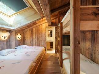 Experience cozy mountain living in this charming bedroom featuring rustic wooden walls and exposed beams.