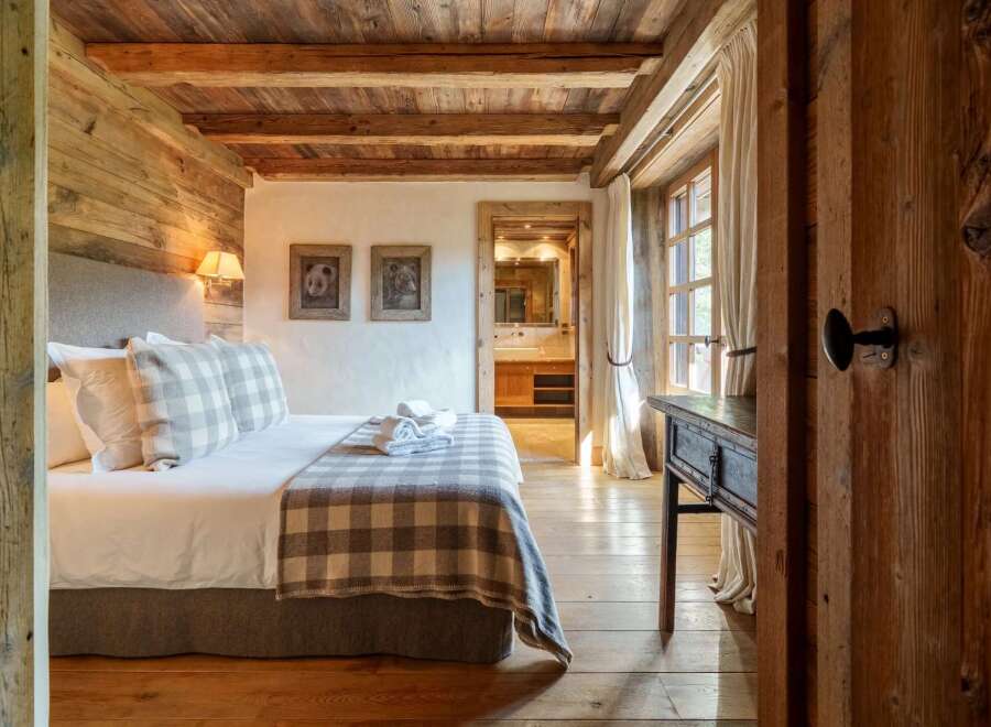 Experience rustic charm in this beautifully appointed bedroom, featuring exposed wooden beams and walls that exude warmth and character.