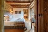 Experience rustic charm in this beautifully appointed bedroom, featuring exposed wooden beams and walls that exude warmth and character.