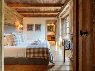 Experience rustic charm in this beautifully appointed bedroom, featuring exposed wooden beams and walls that exude warmth and character.