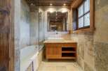 Experience rustic charm in this beautifully appointed bathroom, featuring a luxurious bathtub and a modern vessel sink atop a wooden vanity.