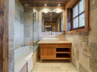 Experience rustic charm in this beautifully appointed bathroom, featuring a luxurious bathtub and a modern vessel sink atop a wooden vanity.
