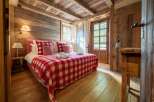 Experience rustic charm in this cozy bedroom, featuring a plush bed adorned with a classic red and white checkered blanket and matching pillows.