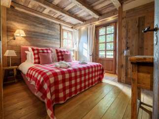 Experience rustic charm in this cozy bedroom, featuring a plush bed adorned with a classic red and white checkered blanket and matching pillows.