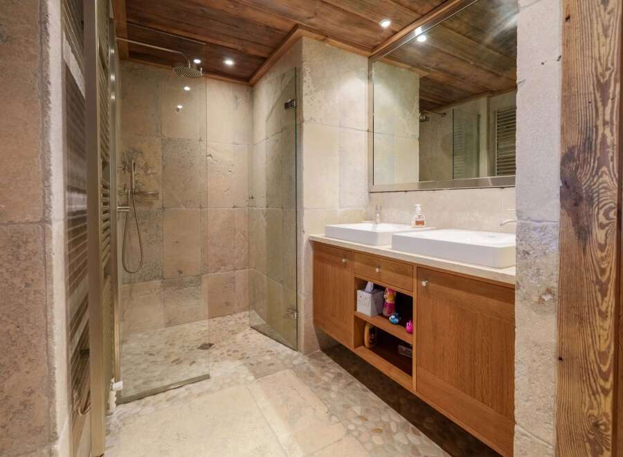 Experience rustic luxury in this stunning bathroom, featuring a spacious walk-in shower with stone tile walls and a pebble floor.