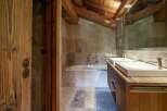 Experience rustic luxury in this charming bathroom, featuring a deep soaking tub surrounded by natural stone and pebble accents.