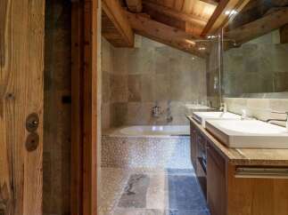 Experience rustic luxury in this charming bathroom, featuring a deep soaking tub surrounded by natural stone and pebble accents.