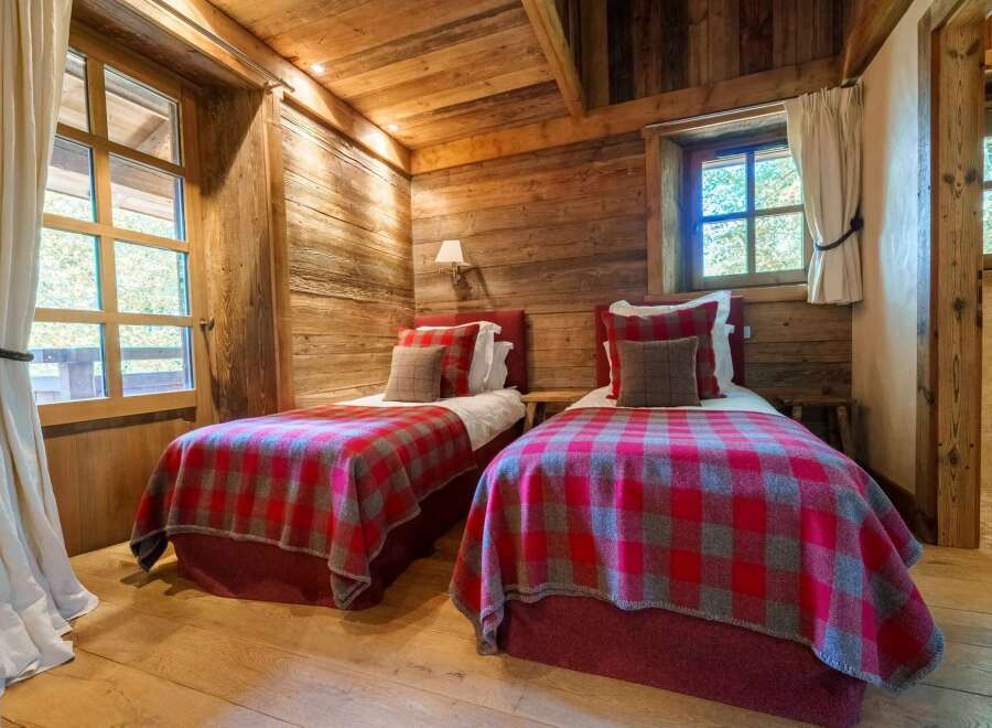 Experience rustic charm in this cozy bedroom, featuring two twin beds adorned with classic red and grey plaid blankets.