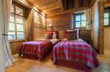 Experience rustic charm in this cozy bedroom, featuring two twin beds adorned with classic red and grey plaid blankets.