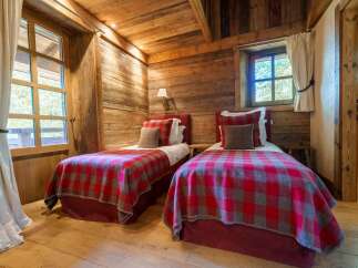 Experience rustic charm in this cozy bedroom, featuring two twin beds adorned with classic red and grey plaid blankets.