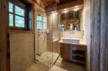 Experience rustic luxury in this charming bathroom, featuring a spacious walk-in shower with a rainfall showerhead and elegant stone tilework.
