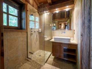 Experience rustic luxury in this charming bathroom, featuring a spacious walk-in shower with a rainfall showerhead and elegant stone tilework.