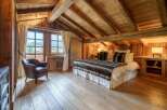 Experience rustic luxury in this charming attic bedroom, featuring exposed wooden beams and a cozy, inviting atmosphere.