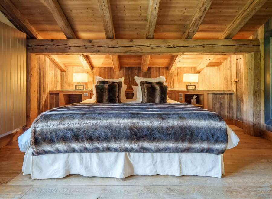 Experience rustic luxury in this charming bedroom, featuring a plush bed adorned with a cozy, striped faux fur throw and decorative pillows.