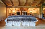 Experience rustic luxury in this charming bedroom, featuring a plush bed adorned with a cozy, striped faux fur throw and decorative pillows.