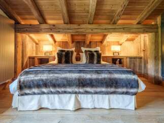 Experience rustic luxury in this charming bedroom, featuring a plush bed adorned with a cozy, striped faux fur throw and decorative pillows.