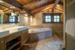 Experience rustic luxury in this charming bathroom, featuring a deep soaking tub nestled against a stone accent wall.