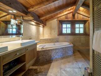 Experience rustic luxury in this charming bathroom, featuring a deep soaking tub nestled against a stone accent wall.