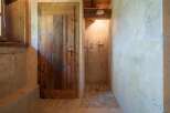 Experience rustic charm in this bathroom featuring a unique wooden door and a spacious walk-in shower.