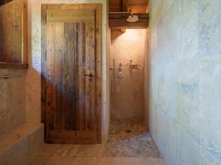 Experience rustic charm in this bathroom featuring a unique wooden door and a spacious walk-in shower.