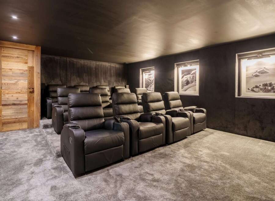 Experience ultimate comfort in this home theater, featuring plush black leather recliners arranged on tiered carpeting for optimal viewing.