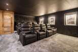 Experience ultimate comfort in this home theater, featuring plush black leather recliners arranged on tiered carpeting for optimal viewing.