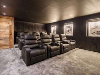 Experience ultimate comfort in this home theater, featuring plush black leather recliners arranged on tiered carpeting for optimal viewing.