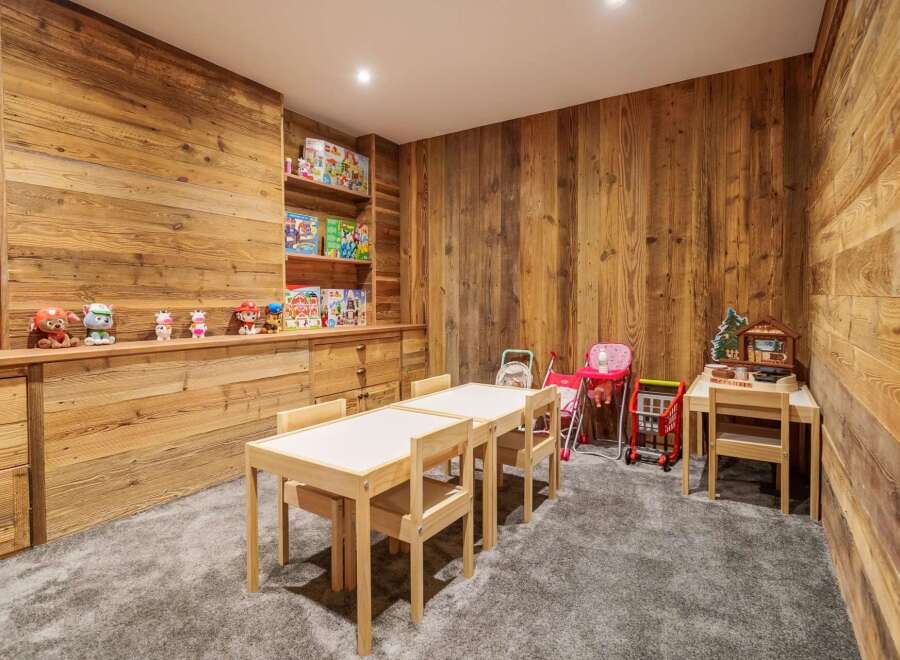This charming children's playroom features rustic wooden walls and built-in shelving, creating a warm and inviting atmosphere.